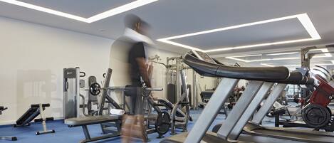 A gym with treadmills, weight machines, and a blue floor.