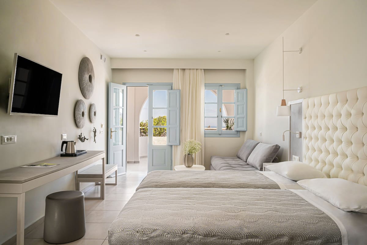 A modern bedroom with a large bed, a desk, and a television.