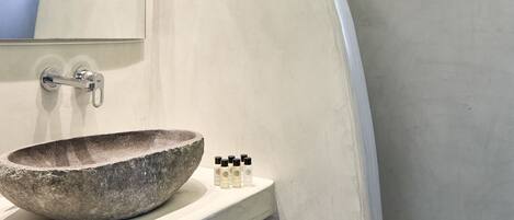 Une salle de bain moderne avec un grand lavabo incurvé, une douche et un miroir.