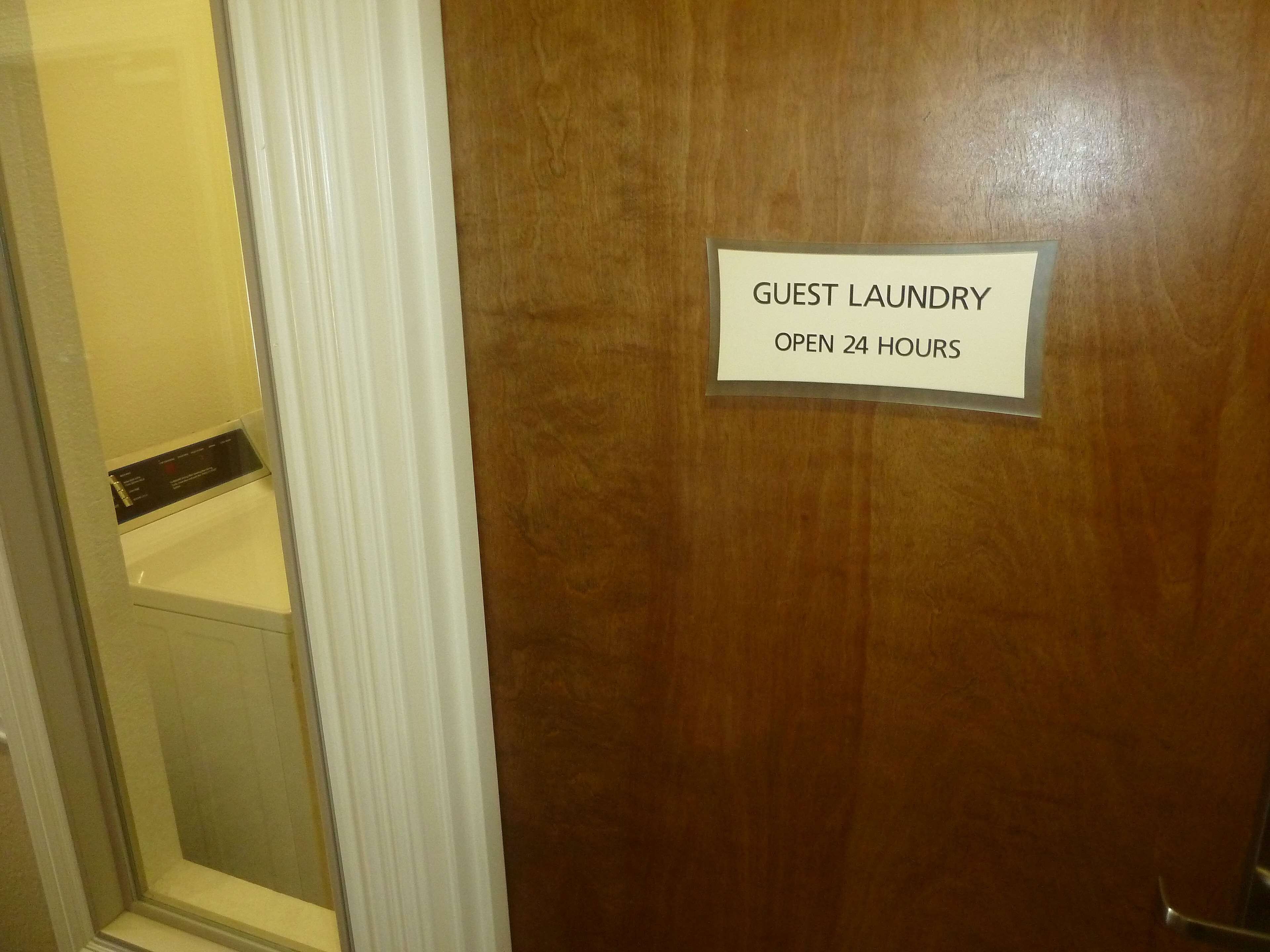 Una puerta con un cartel que dice "GUEST LAUNDRY OPEN 24 HOURS".