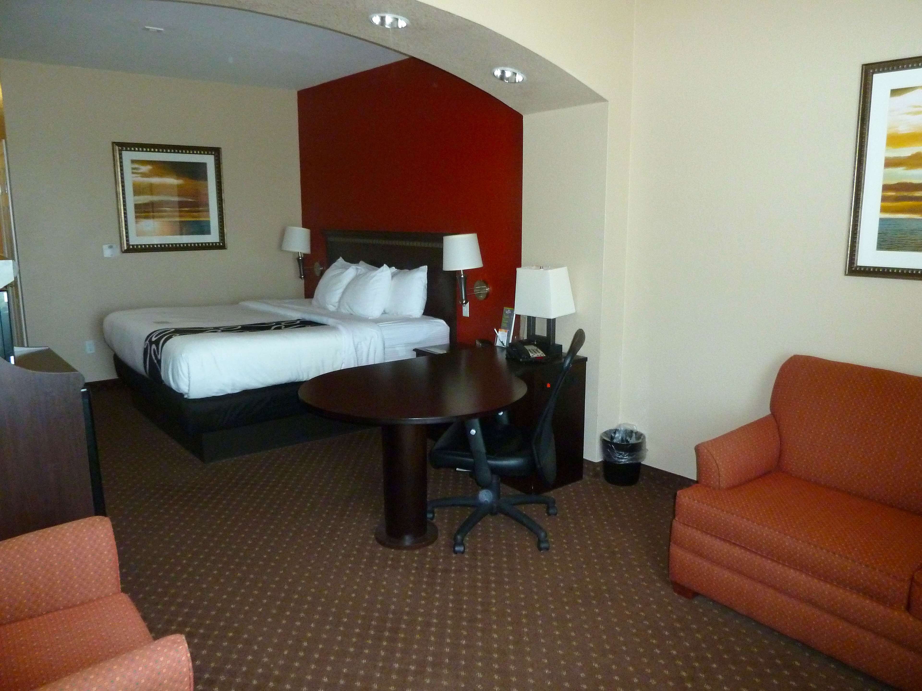 A hotel room with a bed, a desk, a chair, and a sofa.