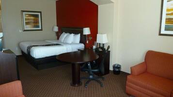 A hotel room with a bed, a desk, a chair, and a sofa.
