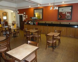 Un restaurante con varias mesas y sillas, una barra con distintos productos y un suelo de baldosas.
