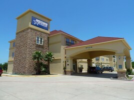 Una entrada de hotel con una torre de piedra, tejado de tejas rojas y cielo azul despejado.