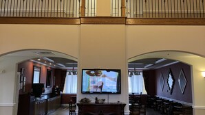 Un'ampia zona giorno con soffitto alto, camino e televisore a parete. Sono presenti due divani e un'area pranzo con tavoli.