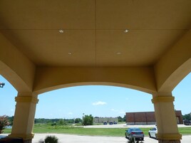 Un espacio al aire libre techado con vista despejada a un estacionamiento y un edificio al fondo.
