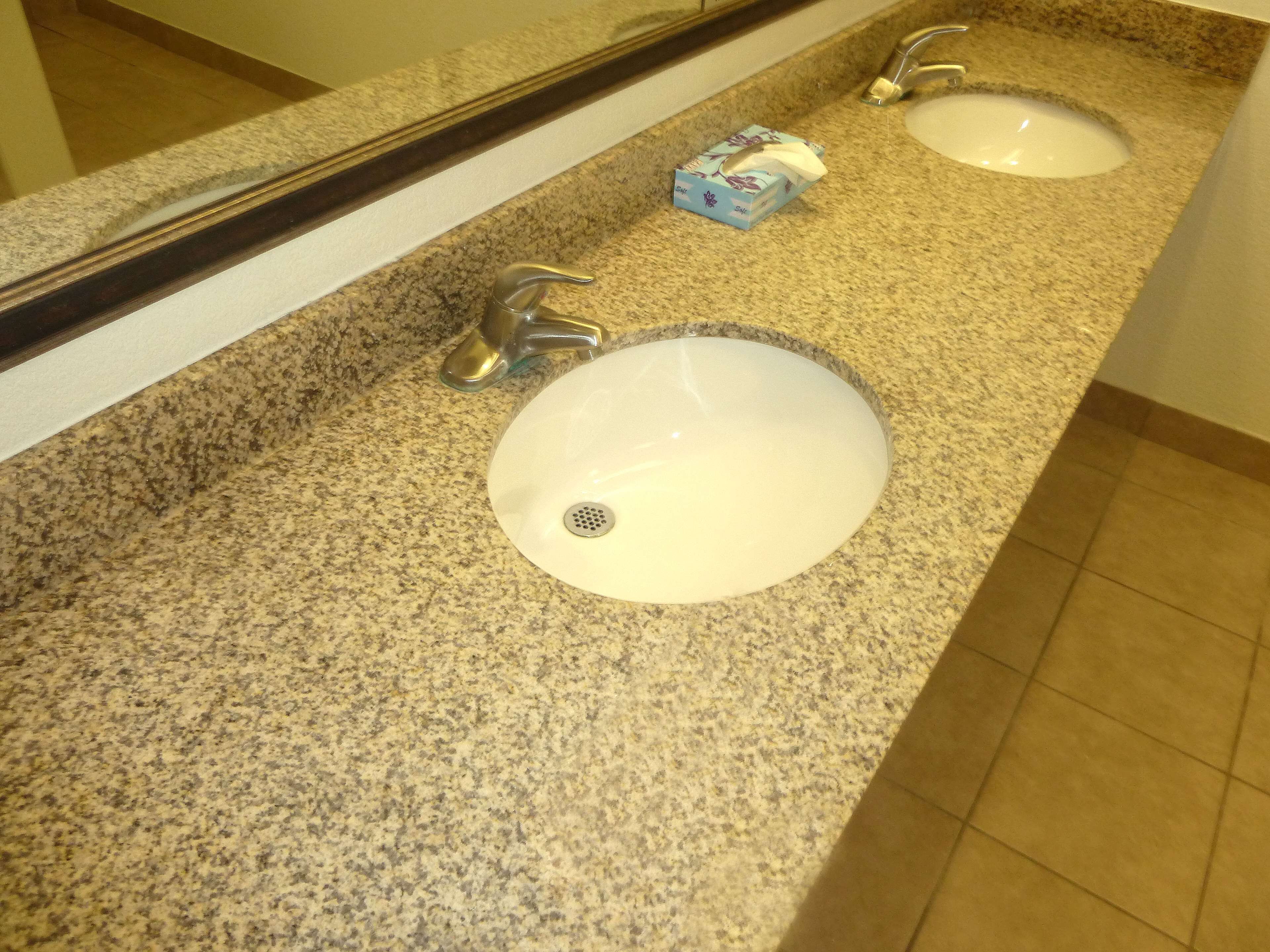 A bathroom with two sinks, each with a faucet and a tissue box.