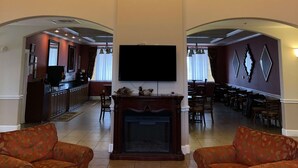 Un'ampia zona giorno con camino, due poltrone, una TV a schermo piatto e un'area pranzo con numerosi posti a sedere.