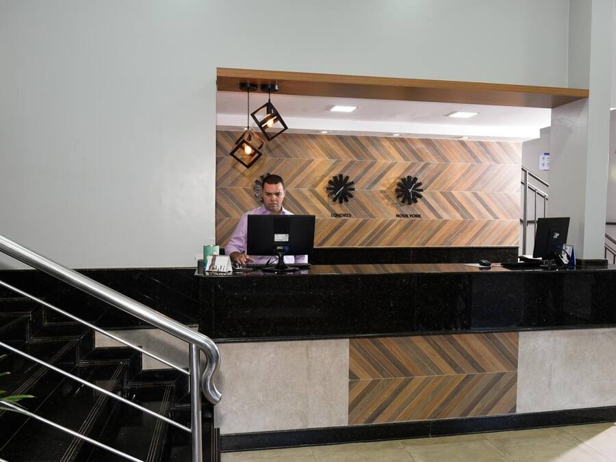 A reception desk with a modern design, featuring a black marble counter and a herringbone patterned wall.