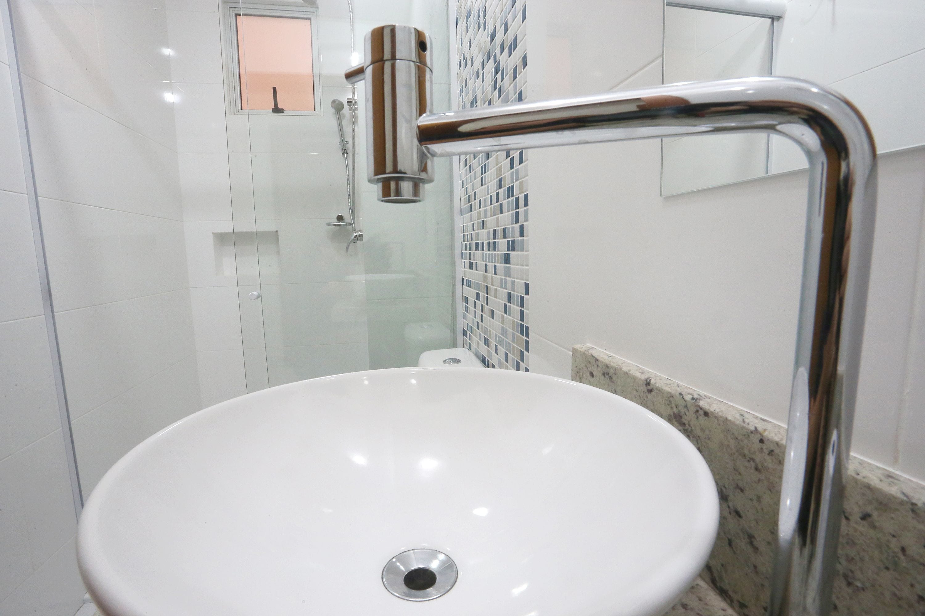 A bathroom with a white sink, chrome fixtures, and a tiled shower area.