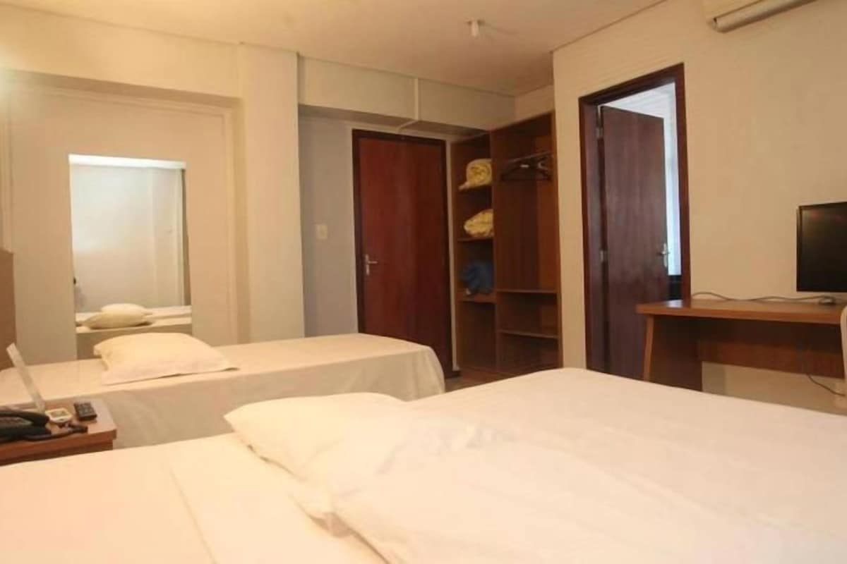 A hotel room with two beds, a desk, a television, and a wardrobe.