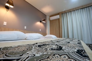 Ein Hotelzimmer mit einem Bett, zwei Wandlampen und einem Fenster mit Vorhängen.