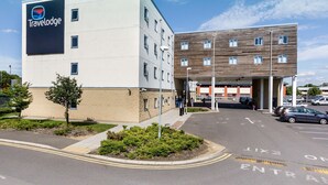 Ein Travelodge Hotel mit modernem Design, das ein großes Schild und einen Parkplatz zeigt.