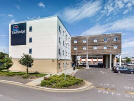 Un hotel Travelodge con un diseño moderno, que presenta un letrero grande y un estacionamiento.
