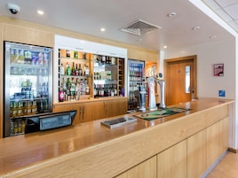 Zona de bar con mostrador, estanterías llenas de bebidas y grifo de cerveza.