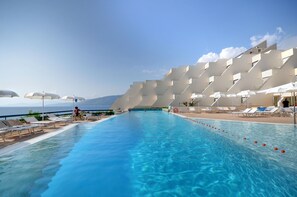 A swimming pool with sun loungers and umbrellas, a clear sky, and a mountainous backdrop. - Grand Hotel San Pietro (Centola)