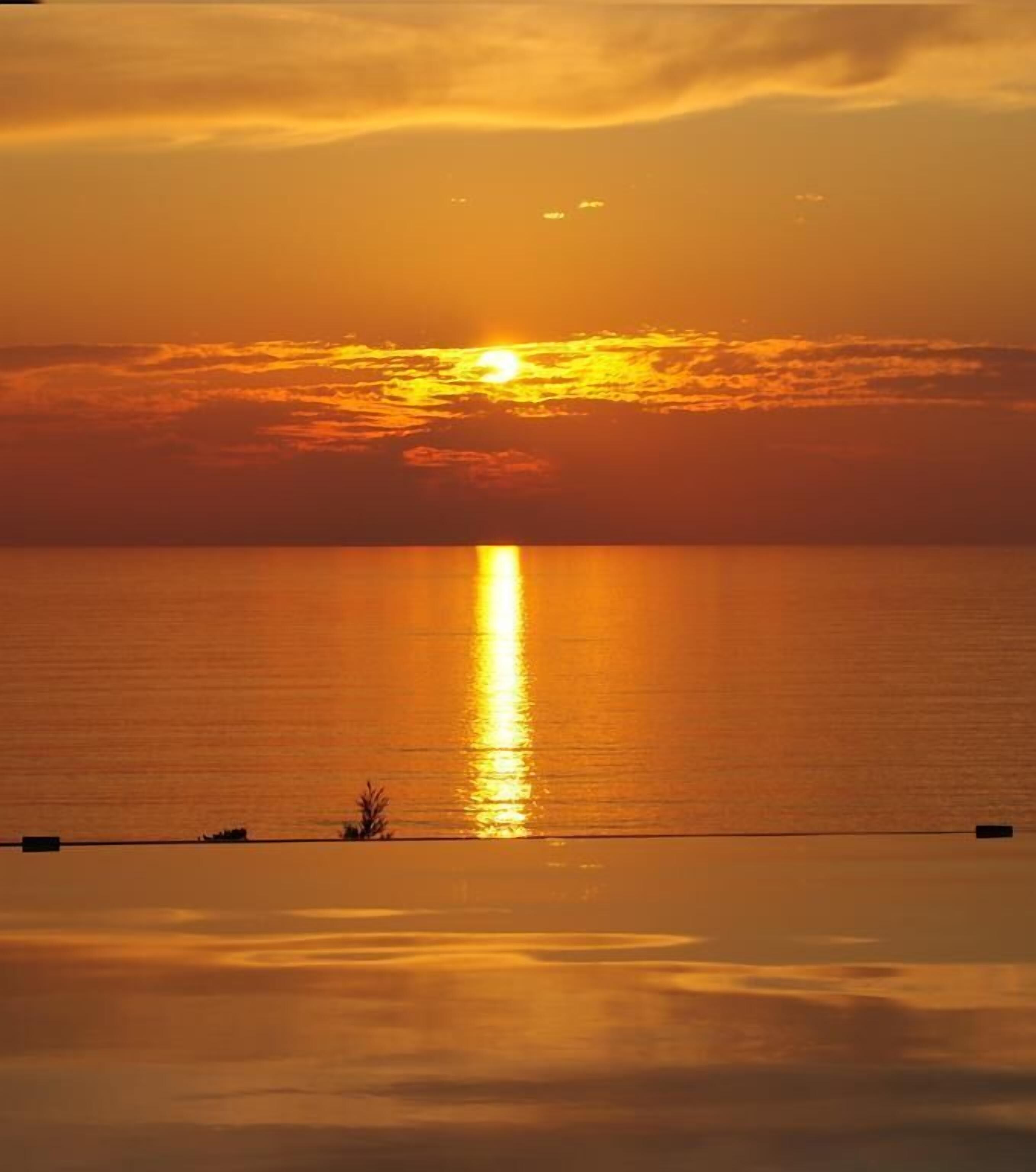 A sunset over a calm sea with a clear horizon.