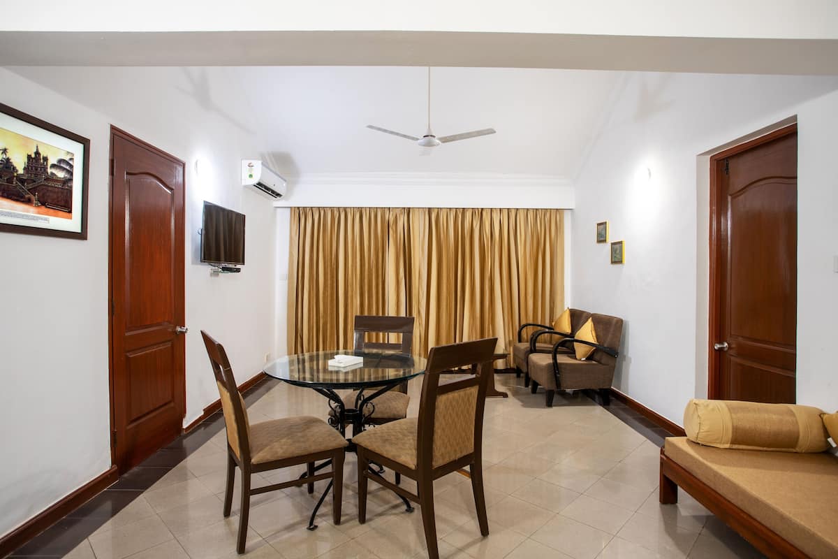 Quarto com uma mesa de jantar, cadeiras, sofá, ventilador de teto e televisão.