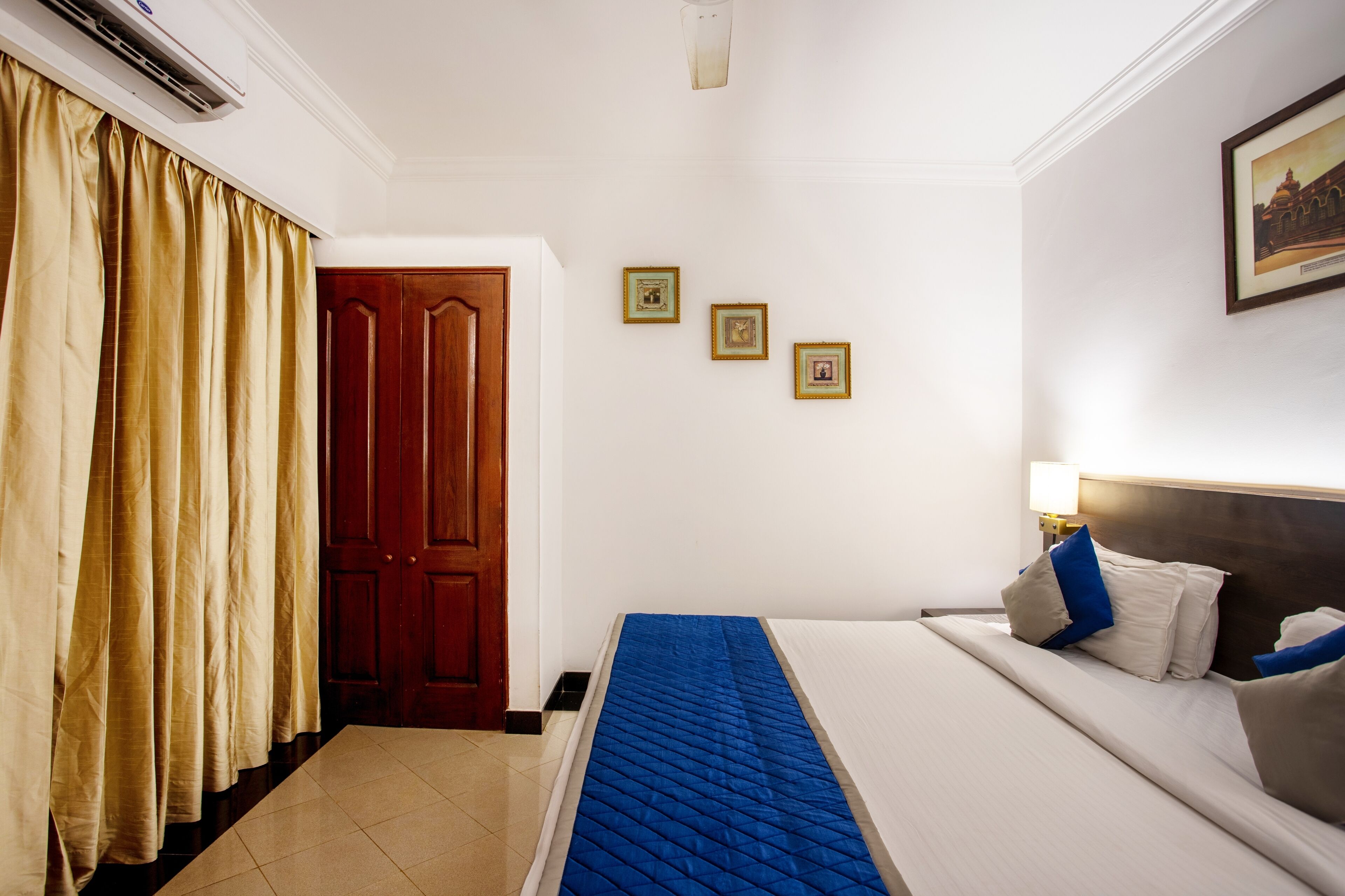 Una habitación de hotel con una cama, una mesita de noche, una lámpara y una puerta.