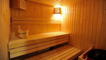 A wooden sauna with benches and a bucket.