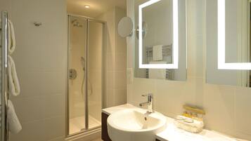 A modern bathroom with a glass-enclosed shower, a white sink, and a mirror above it.