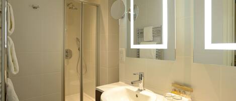 A modern bathroom with a glass-enclosed shower, a white sink, and a mirror above it.