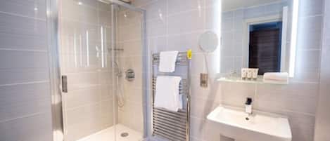 Une salle de bain moderne avec une douche à parois de verre, un lavabo blanc et un miroir au-dessus.