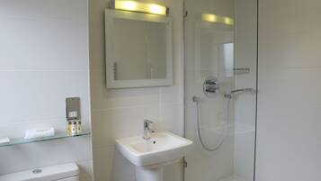 Un baño moderno con inodoro, lavamanos y ducha envuelta en vidrio.