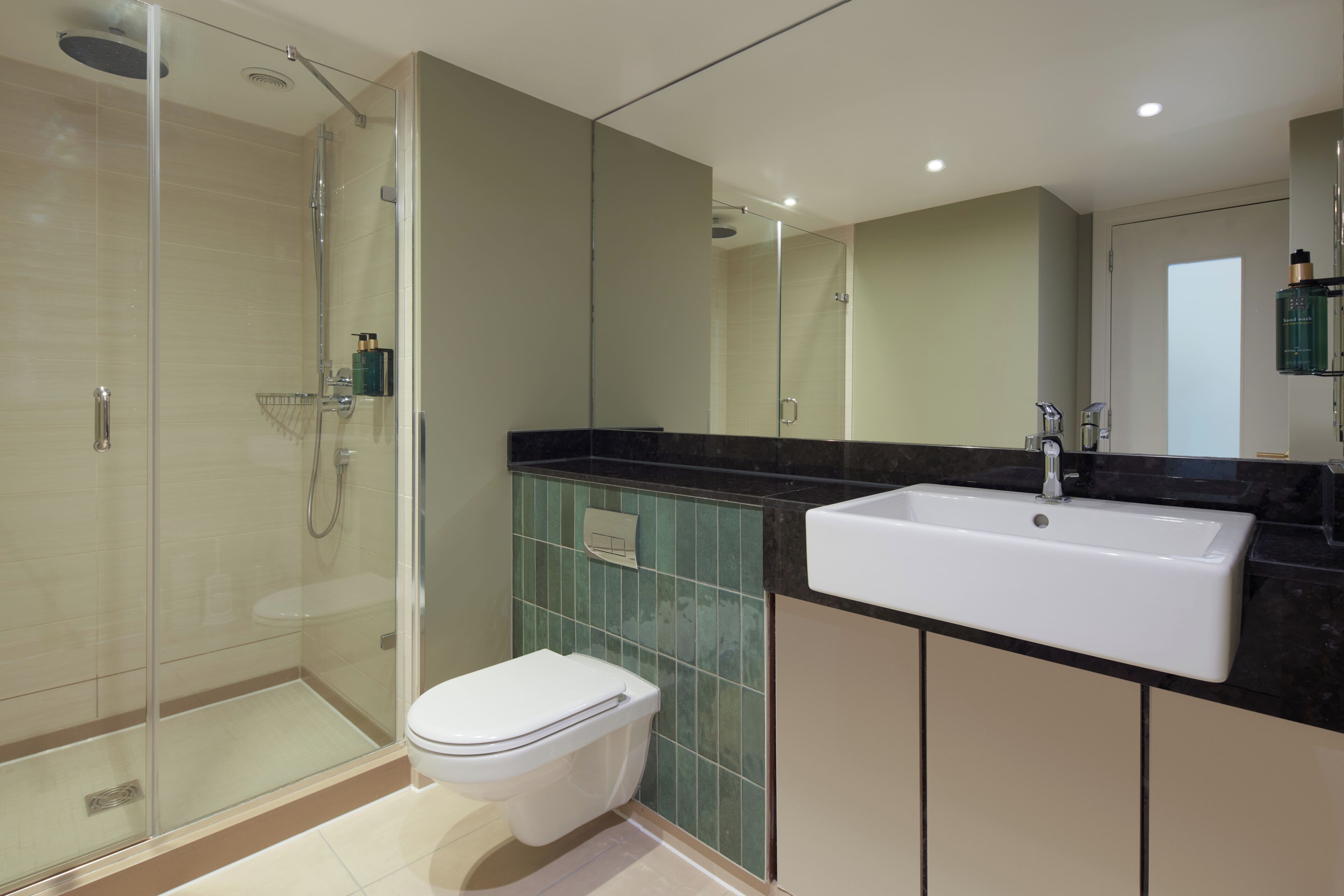 A modern bathroom with a glass-enclosed shower, a white toilet, and a large sink.