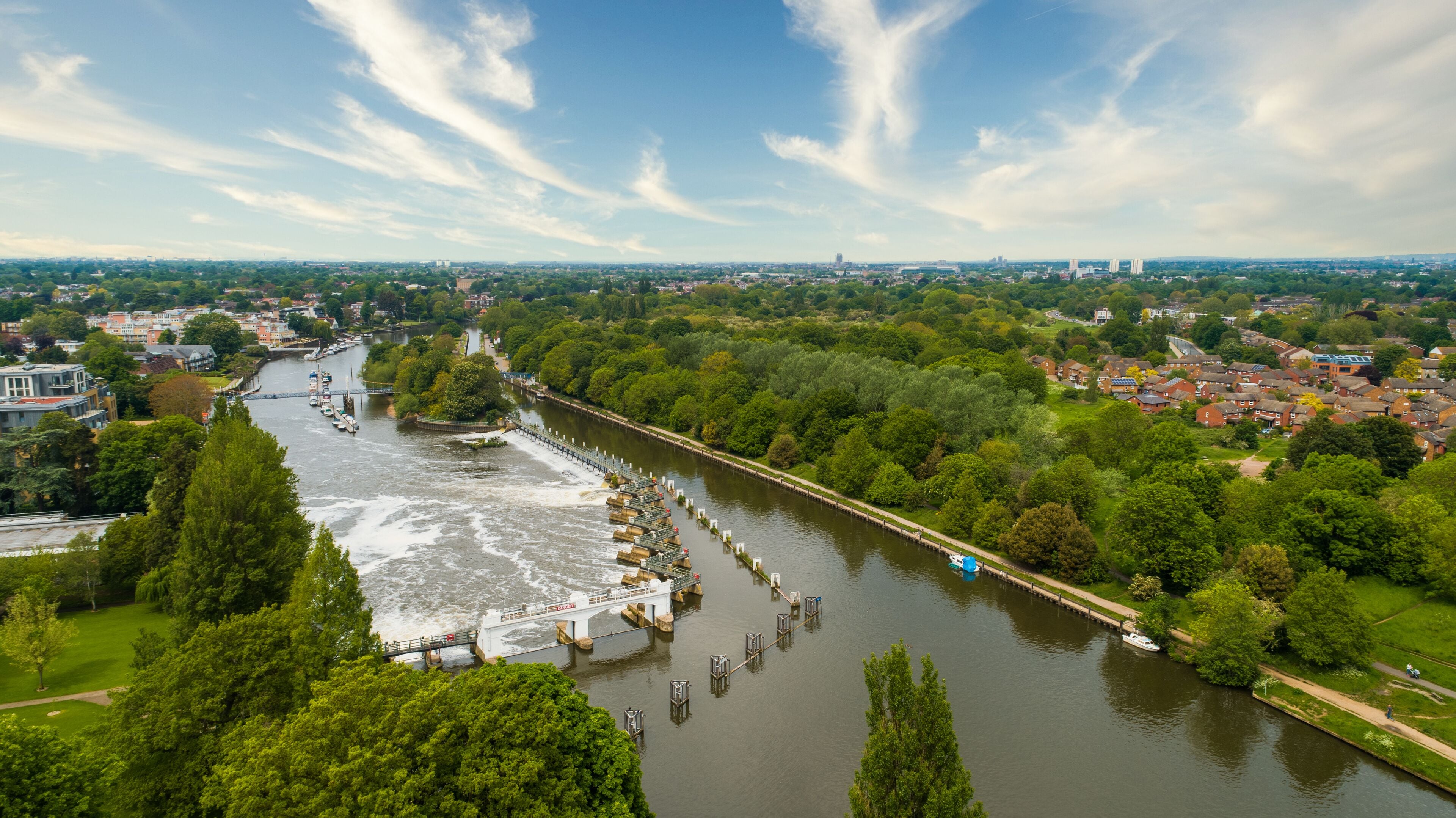 A river with a bridge, surrounded by greenery and residential areas.