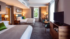 A hotel room with two beds, a TV, a desk, and a chair. - The Lensbury Resort (Teddington)