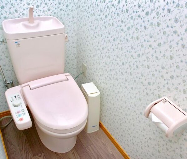 A bathroom with a toilet, bidet, and a small trash bin.