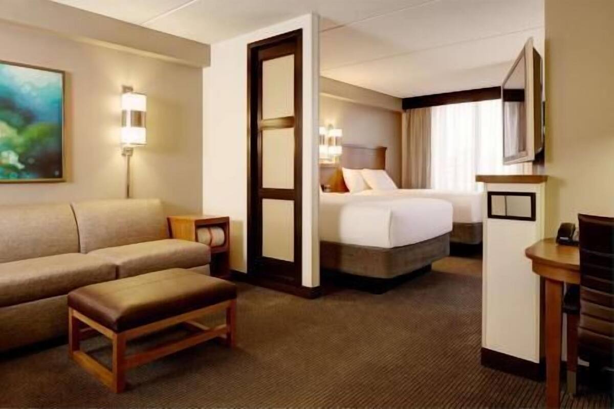 A hotel room with a bed, a sofa, a small table, and a TV.