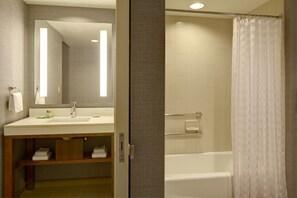 Bathroom features a sink, mirror, and separate shower area with a glass door.