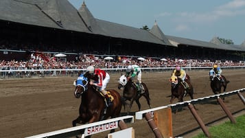 Una pista de carreras de caballos con una tribuna y un cartel que dice "SARATOGA".