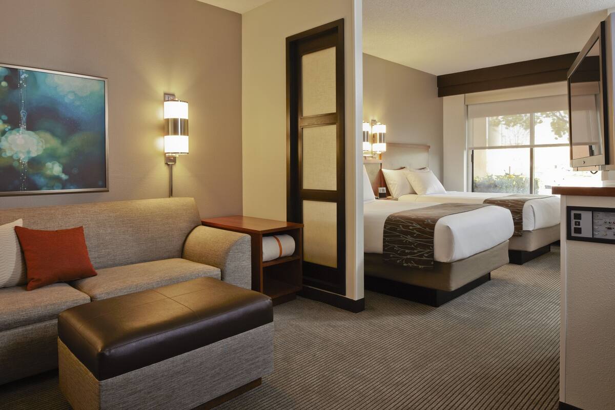 A hotel room with a sofa, a bed, a desk, and a large mirror.