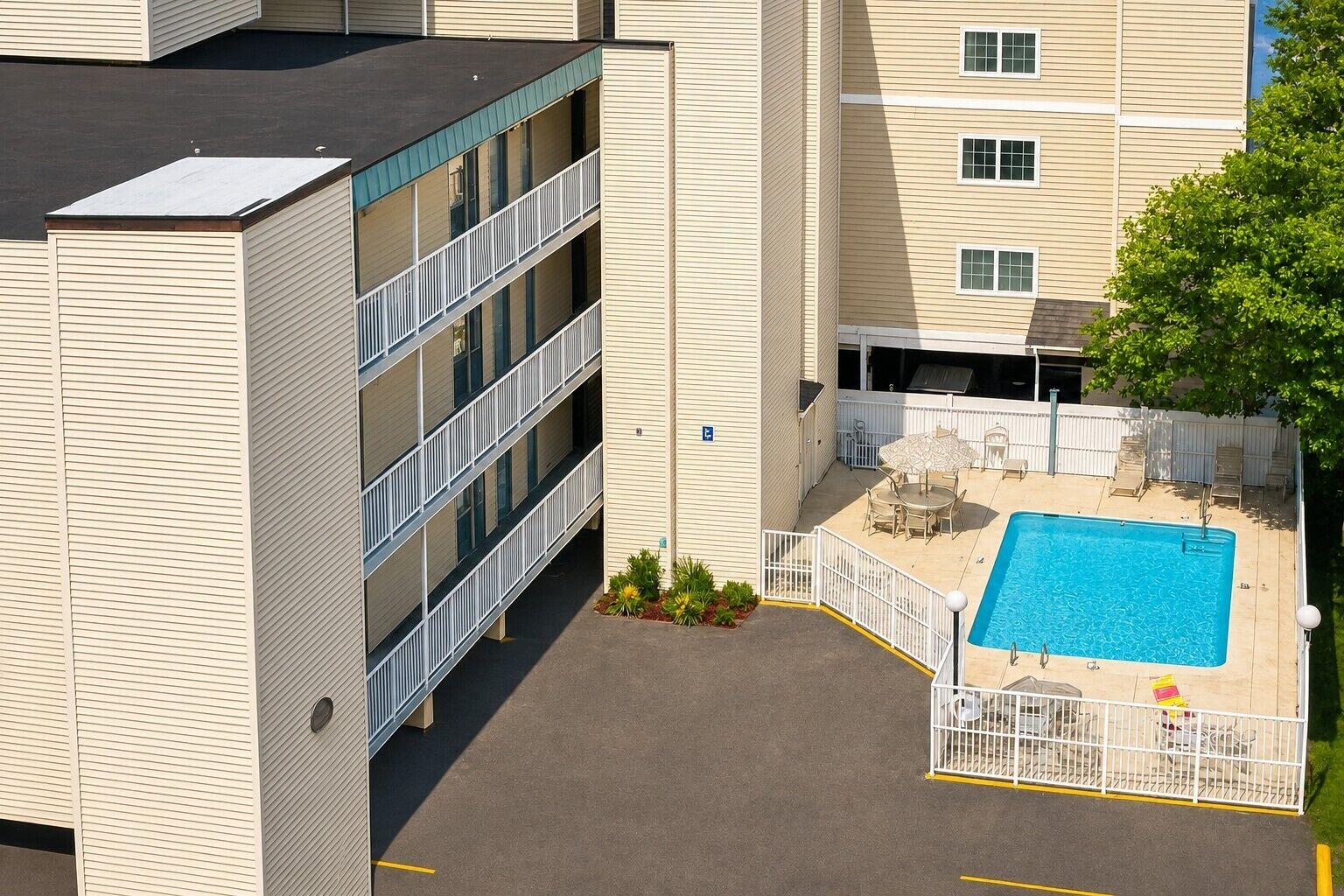 Un edificio de varios pisos con piscina en la azotea, zona de estar al aire libre y patio amurallado.