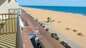 A beachside promenade with a view of the ocean, benches, and a sign indicating a beachside restaurant.
