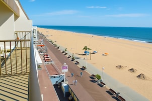 A beachside promenade with a view of the ocean, benches, and a sign indicating a beachside restaurant.