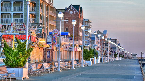 A boardwalk with shops, benches, and street lamps.