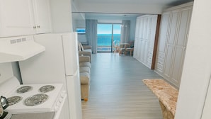 A modern kitchen with white cabinets, a stove, and a view of a balcony with a pool.