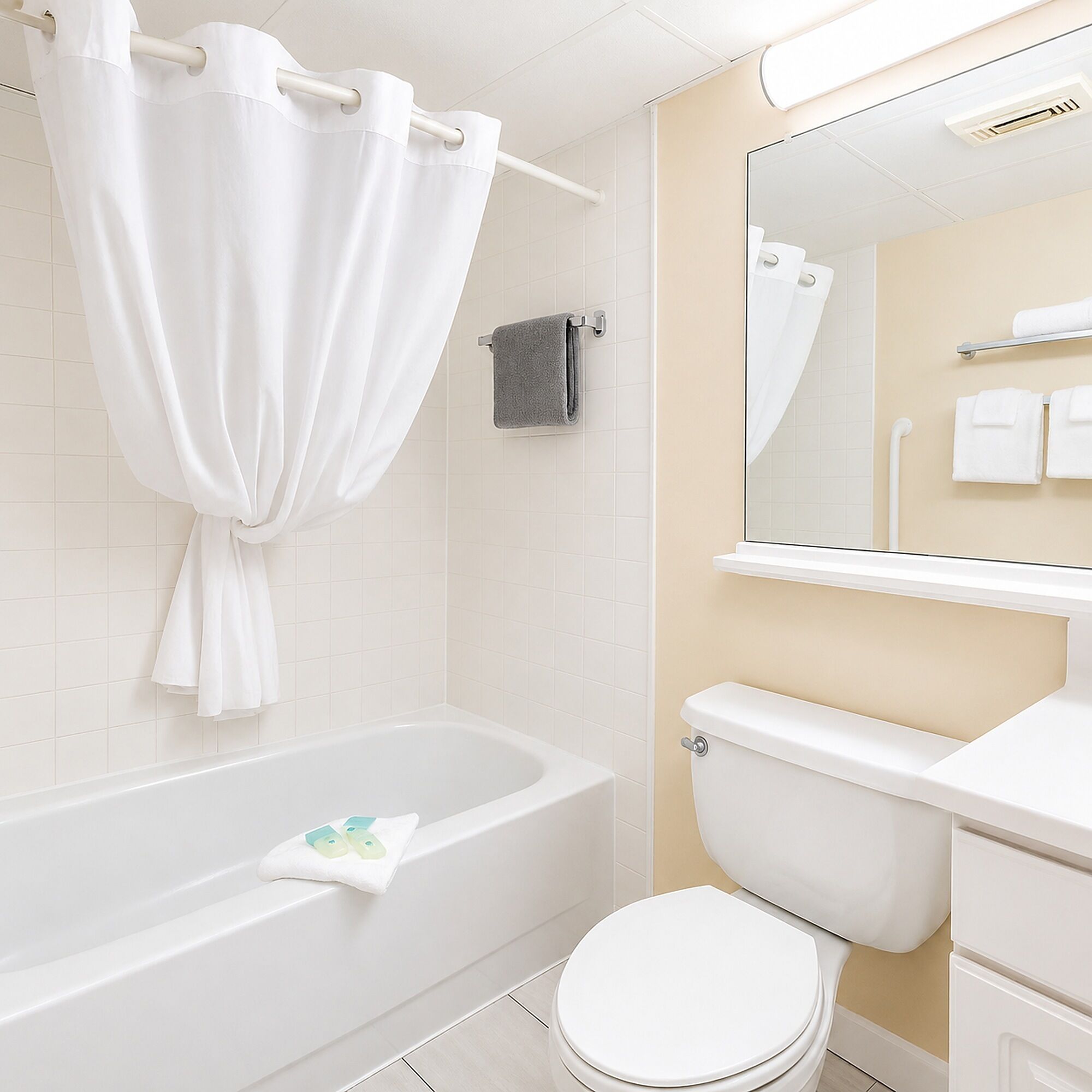 A bathroom with a bathtub, toilet, and a mirror.