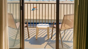 A balcony with a clear view of the beach, featuring a table and chairs.