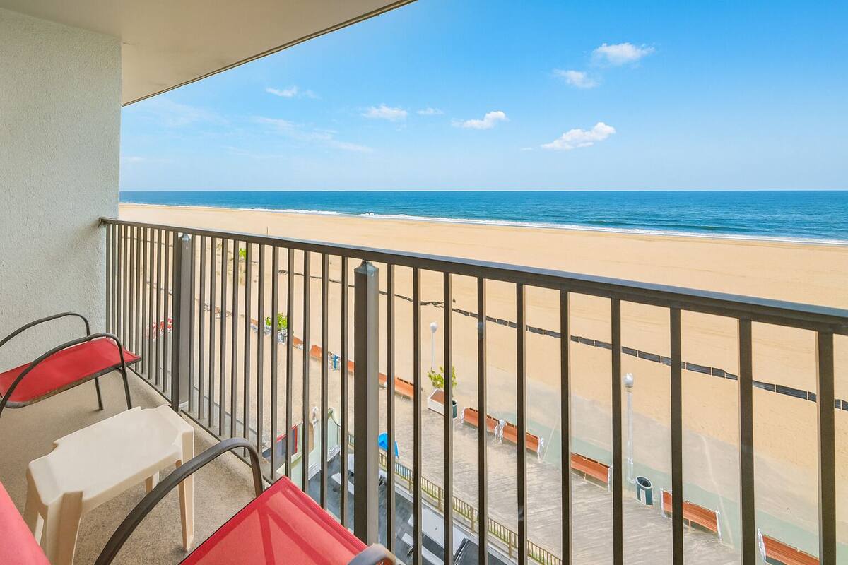 A balcony with a view of a sandy beach and the ocean.