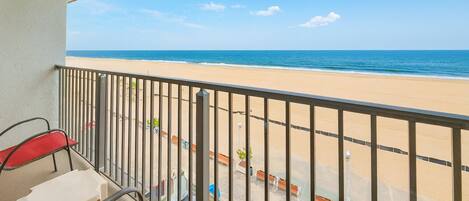 A balcony with a view of a sandy beach and the ocean.
