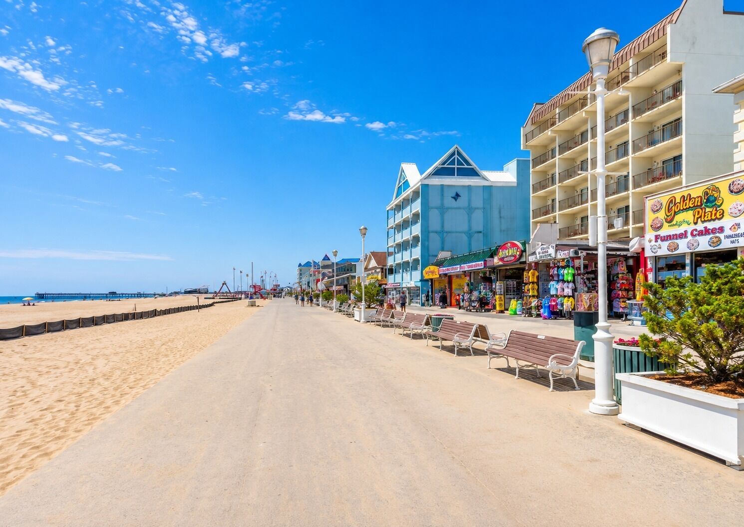 A beachside promenade with a row of shops, including a bakery and a clothing store.