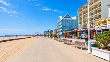 A beachside promenade with a row of shops, including a bakery and a clothing store.