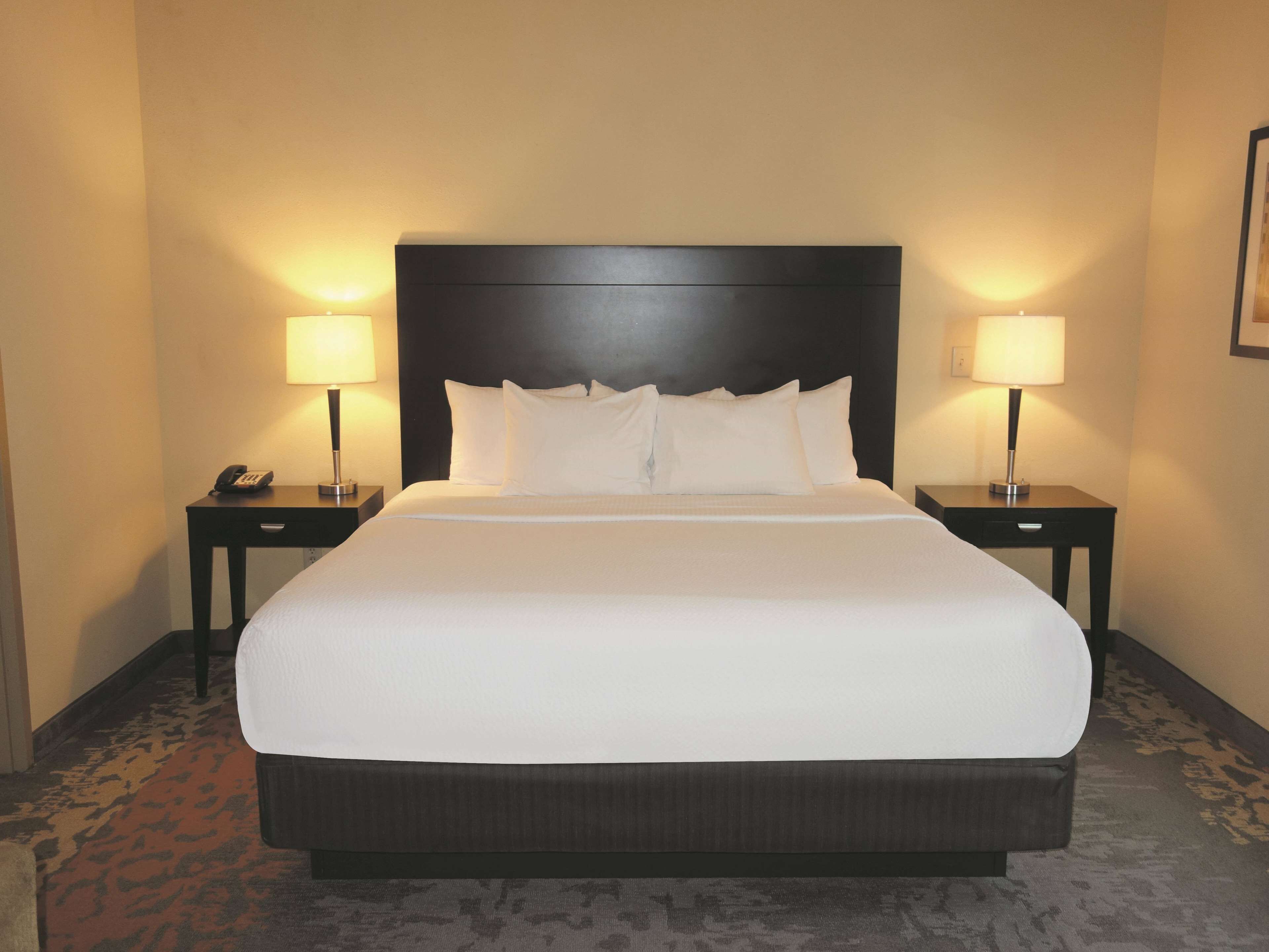 A large bed with a dark headboard, two bedside tables with lamps, and a telephone on one of the tables.