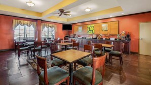 A restaurant with multiple tables and chairs, a ceiling fan, and a kitchen area visible through the windows. - La Quinta Inn & Suites by Wyndham Eastland (Eastland)