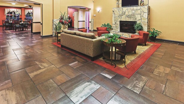 A lobby with a sofa set, red armchairs, a fireplace, and a dining area with tables and chairs. - La Quinta Inn & Suites by Wyndham Eastland (Eastland)